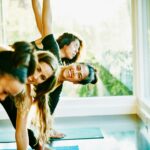 Women in a yoga class practicing Triangle Pose and laughing
