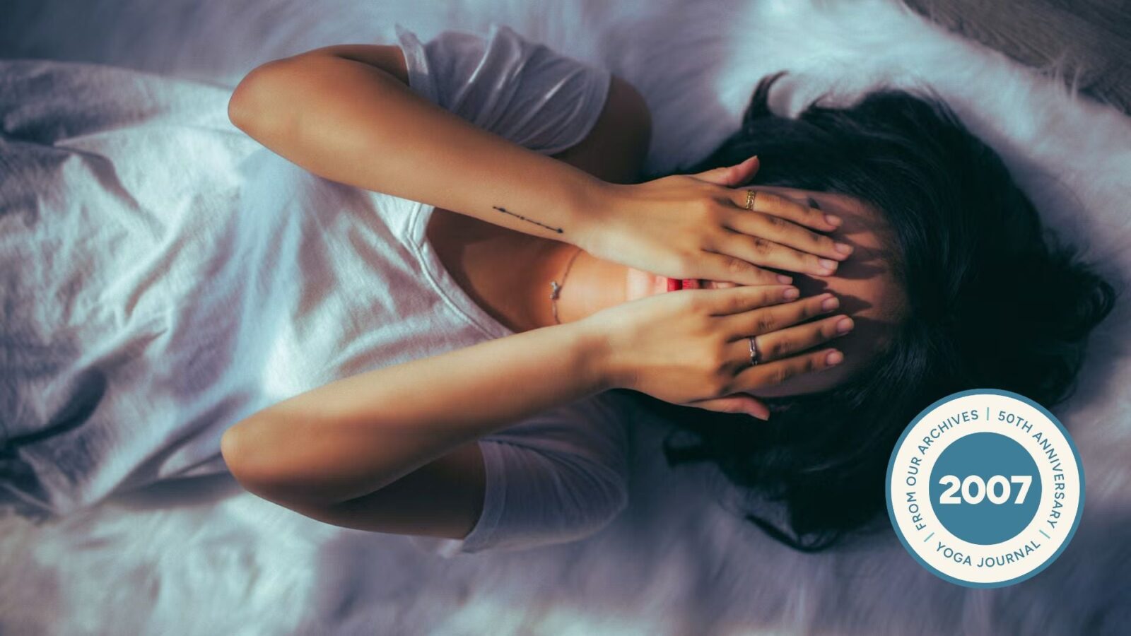 Woman lying on the floor practicing restorative yoga with her hands over her face