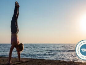 Woman practicing Handstand on the beach at sunset.