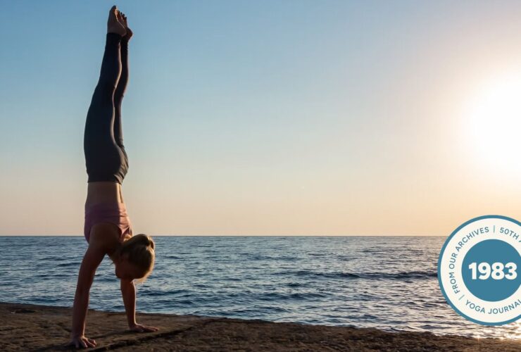 Woman practicing Handstand on the beach at sunset.