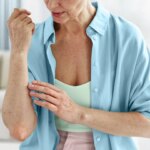 woman looking at a rash on her elbow