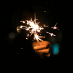 Woman holding a sparkler outside in the night sky