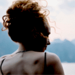 Woman standing outside looking at mountains contemplating her weekly horoscope for December 7-13, 2025.