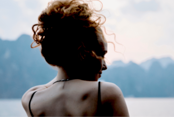 Woman standing outside looking at mountains contemplating her weekly horoscope for December 7-13, 2025.