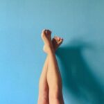 Image of person's legs crossed and resting against a light blue wall.