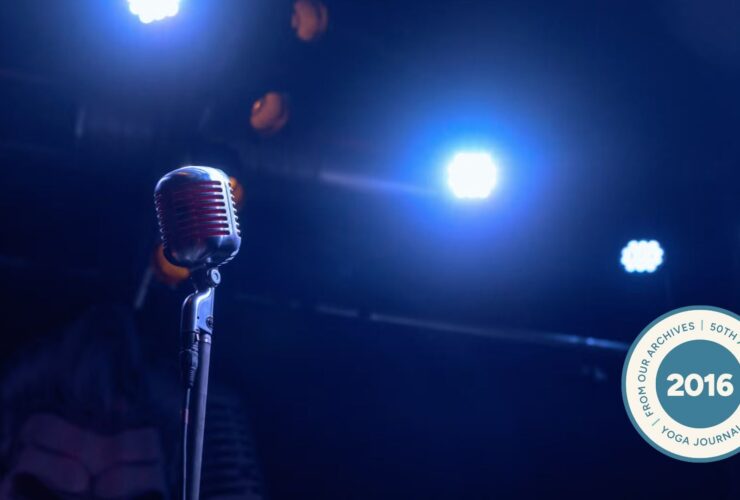 Image of microphone surrounded by darkness with two spotlights blaring down.