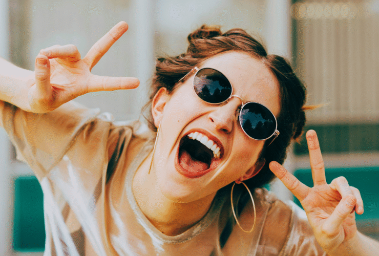 Woman wearing sunglasses and holding up peace fingers about no new years resolutions 2026
