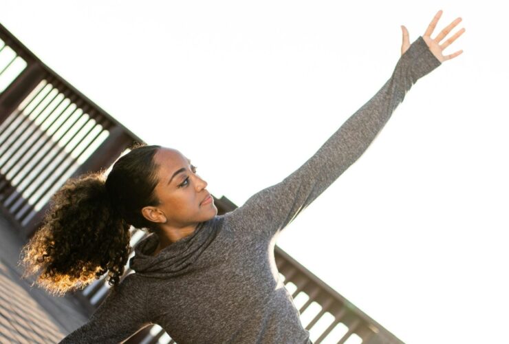 Image of woman outside stretching her arm toward the bright sky.