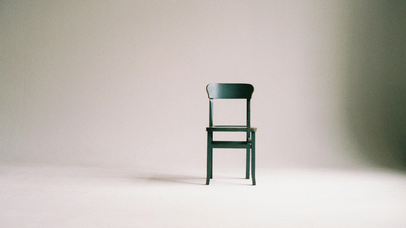 A wooden chair sitting against a wall in preparation for a chair yoga class