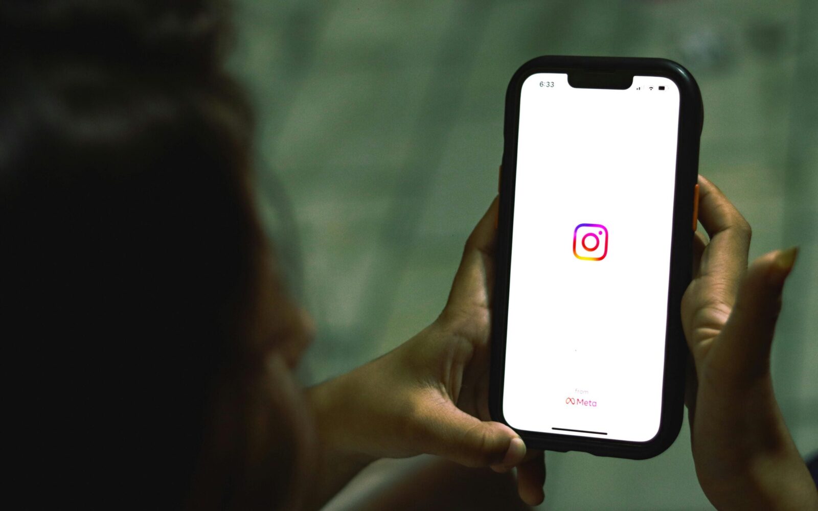Woman holding phone with Instagram logo on the screen.
