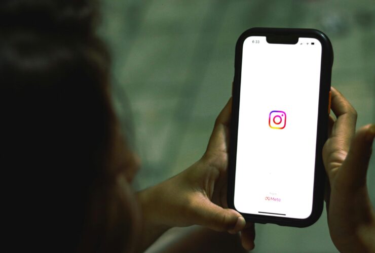 Woman holding phone with Instagram logo on the screen.
