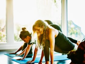 Students in a yoga class transition from Down Dog to Low Lunge