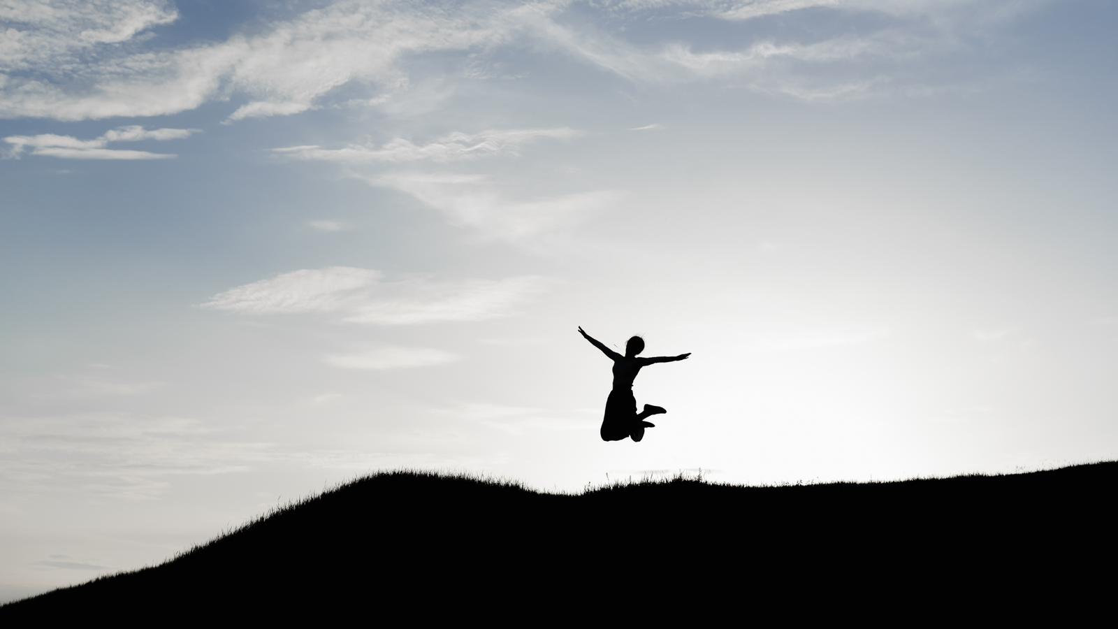 Woman jumping in the air while hiking and contemplating her weekly horoscope