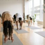 People in yoga class practicing Standing Forward Bend.
