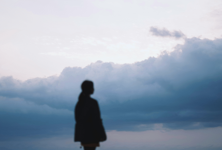Woman staring off into a cloudy, overcast day during winter while contemplating the weekly horoscope for February 1-7, 2026