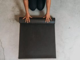 A woman crouching on the ground rolling up one of the best yoga mats