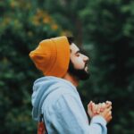 Man with orange beanie on closing his eyes and breathing.