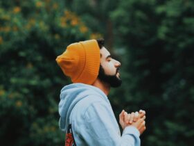 Man with orange beanie on closing his eyes and breathing.