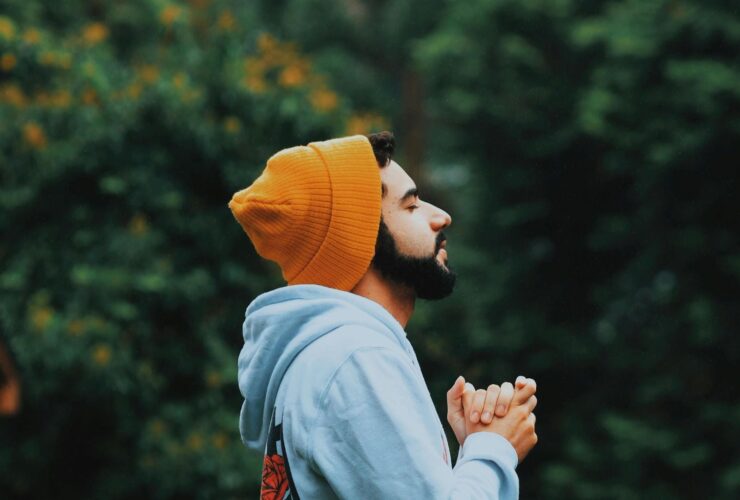 Man with orange beanie on closing his eyes and breathing.