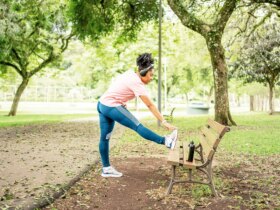 woman in park doing standing hurdler stretch to relieve L5 to S1 exercise to relieve compression