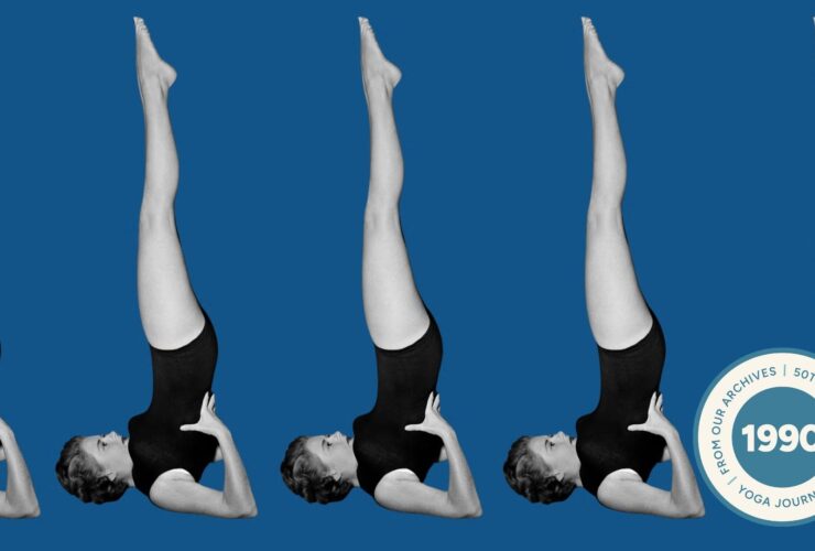 A woman in Shoulderstand against a blue backdrop