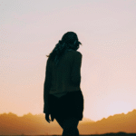 Silhouette of a woman walking toward the sunrise and contemplating her weekly horoscope