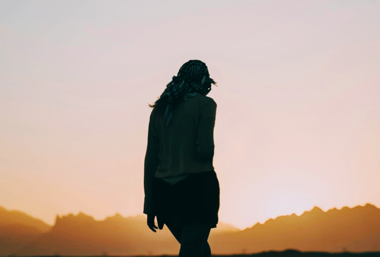 Silhouette of a woman walking toward the sunrise and contemplating her weekly horoscope