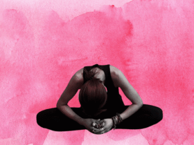 Woman sitting in a seated forward bend with a background of red.