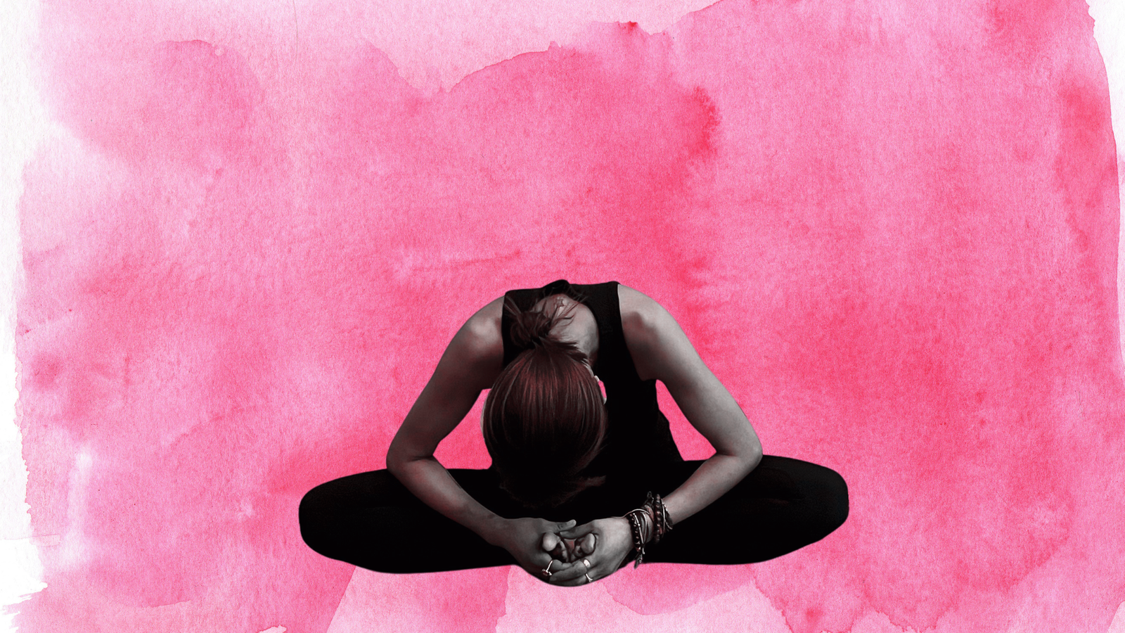 Woman sitting in a seated forward bend with a background of red.