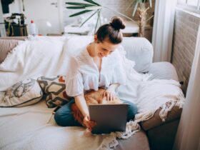 Woman sitting on couch with cat in lap looking at tablet.
