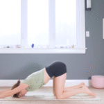 Woman kneeling on a mat with her arms stretched forward and her forehead on the mat in Puppy Pose