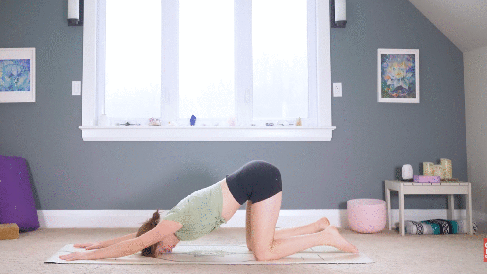Woman kneeling on a mat with her arms stretched forward and her forehead on the mat in Puppy Pose