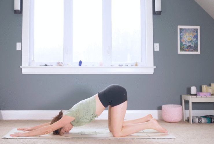 Woman kneeling on a mat with her arms stretched forward and her forehead on the mat in Puppy Pose