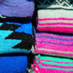 Stacks of colorful Mexican yoga blankets that are the type you'd find in a yoga studio