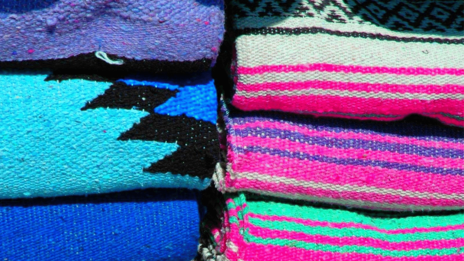 Stacks of colorful Mexican yoga blankets that are the type you'd find in a yoga studio