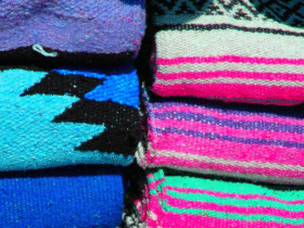 Stacks of colorful Mexican yoga blankets that are the type you'd find in a yoga studio
