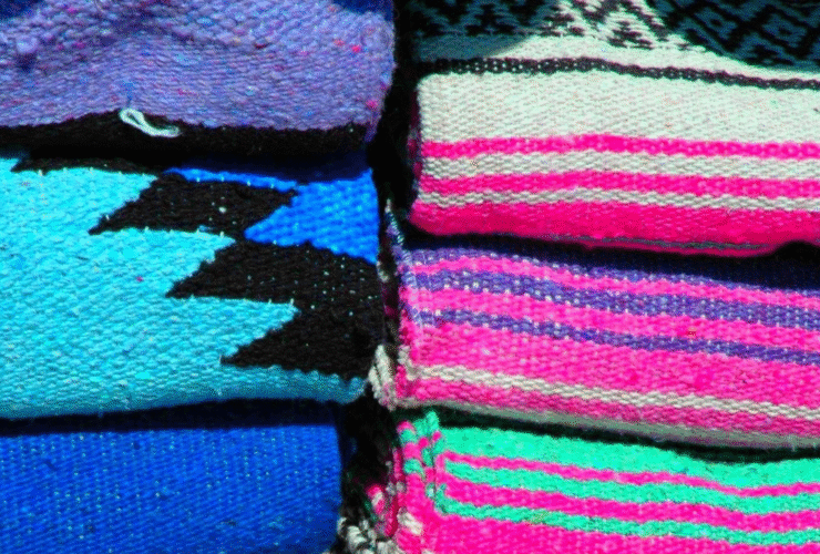 Stacks of colorful Mexican yoga blankets that are the type you'd find in a yoga studio
