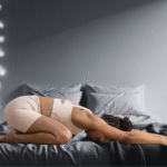 A woman practicing Child's Pose on a bed, part of a yoga for sleep flow