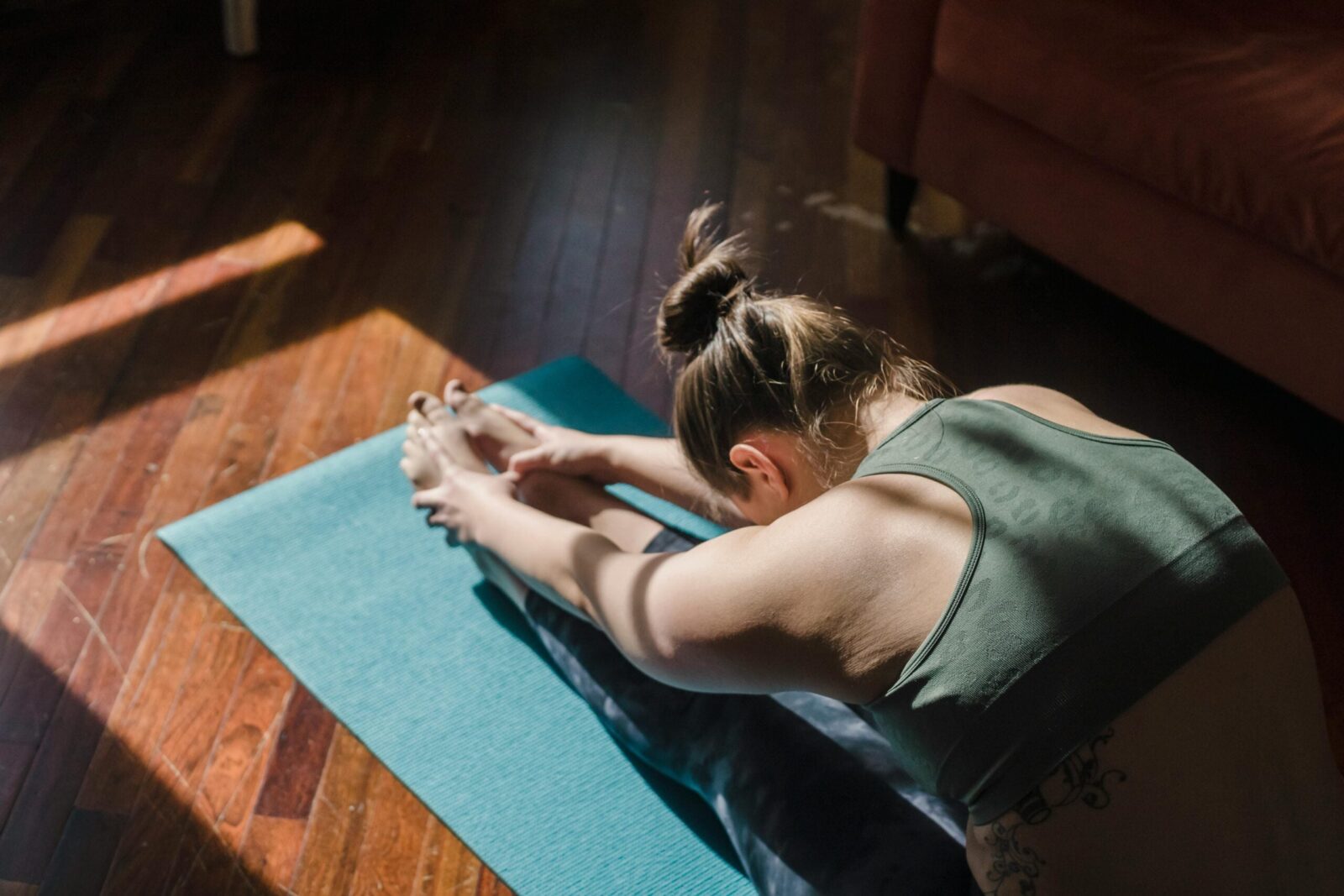 Woman practicing Forward Fold in dark room.