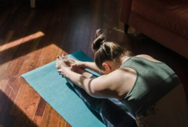 Woman practicing Forward Fold in dark room.