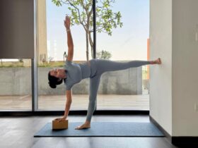 Yoga instructor Riya Davda practicing Half Moon Pose against a wall.