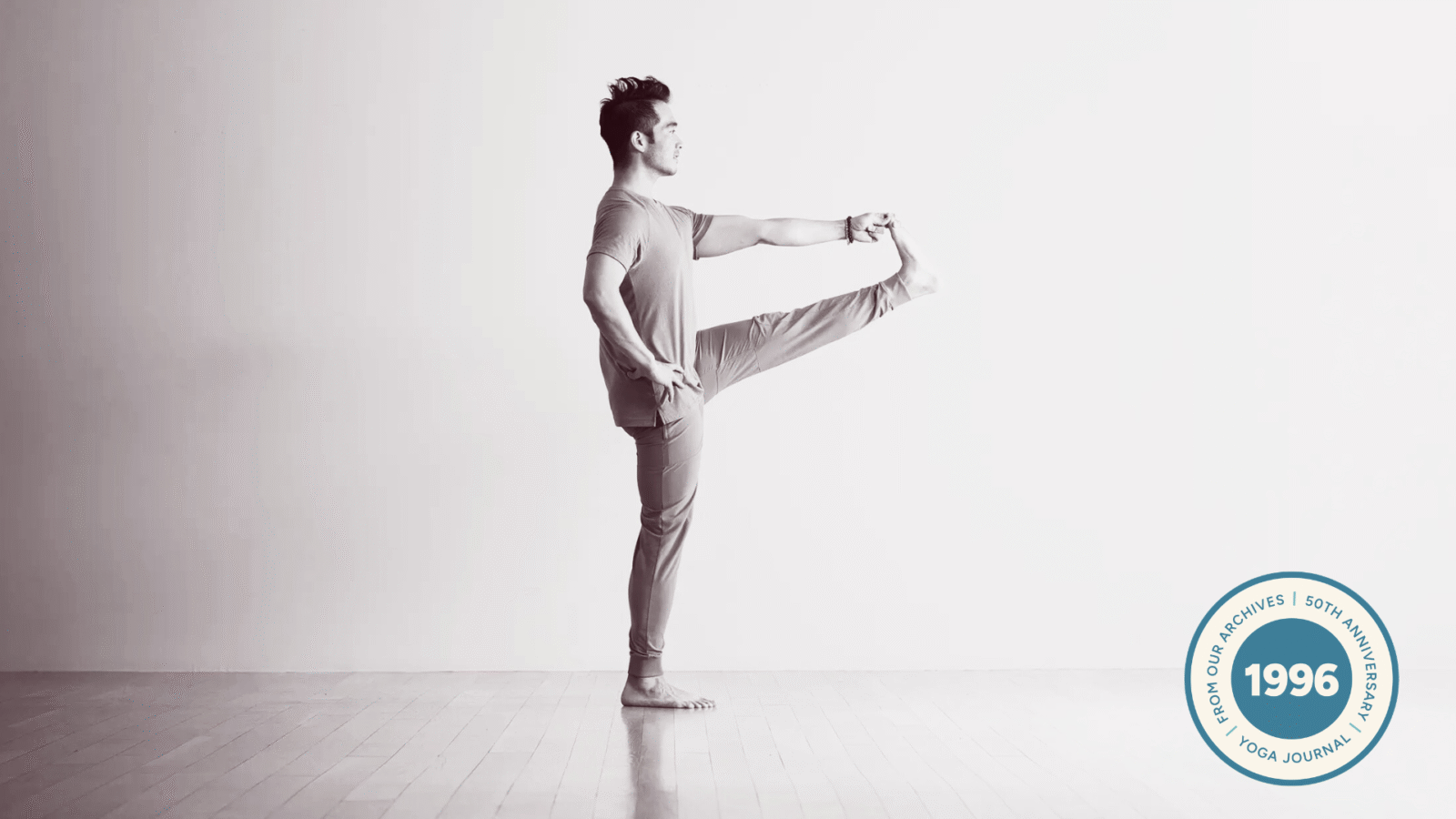 Man in a standing balancing pose with his hand reaching for his lifted foot in Utthita Hasta Padangusthasana