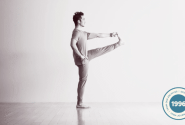 Man in a standing balancing pose with his hand reaching for his lifted foot in Utthita Hasta Padangusthasana