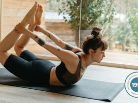 Woman lying on her belly and reaching for her arms in preparation for Side Bow Pose (Parsva Dhanurasana)