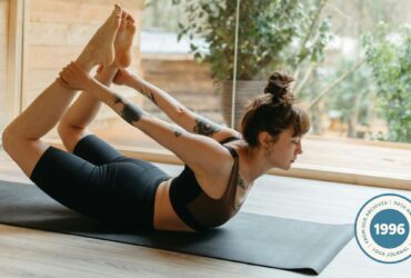 Woman lying on her belly and reaching for her arms in preparation for Side Bow Pose (Parsva Dhanurasana)