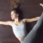 Woman practicing Jathara Parivartanasana.