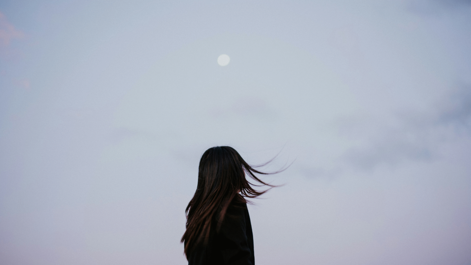 Woman silhouette against a lavender evening with a full Moon