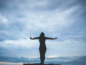 Woman silhouette standing on a cliff near a beach with dark clouds considering the weekly horoscope for November 17-23, 2024.