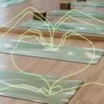 Heart hands over the backdrop of an empty yoga studio