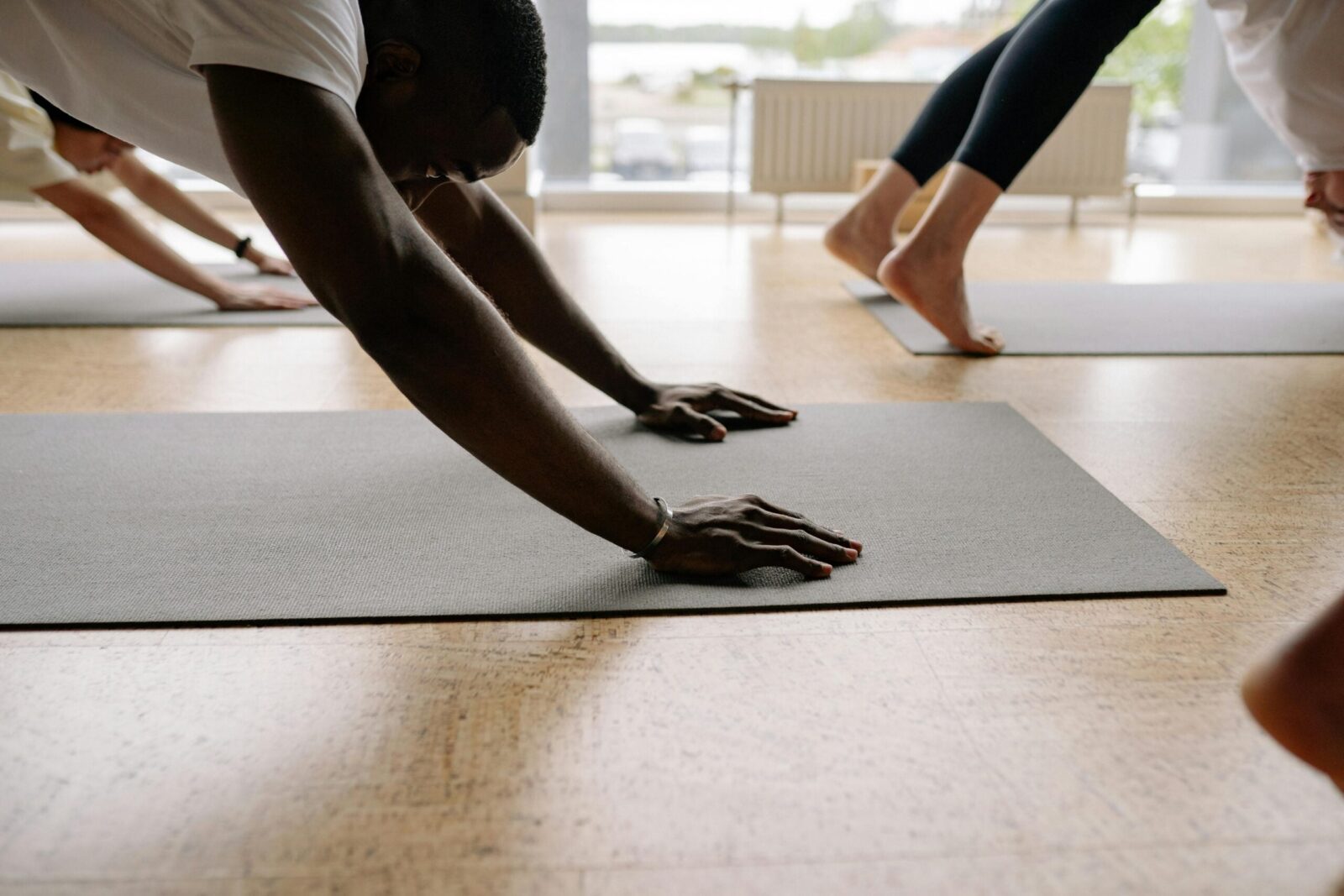 Close-up of man's hands in Downward Facing Dog in yoga class.